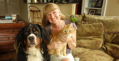 Person sitting with dog, cat, and bird