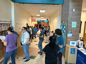 Busy hallway during cat adoption event with many people being helped by staff