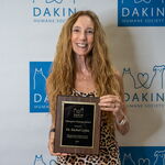Award recipient standing with an award plaque