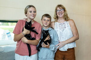 Family holding 2 black kittens at Dakin