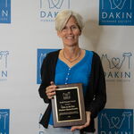 Award recipient standing with an award plaque