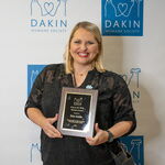Award recipient standing with an award plaque